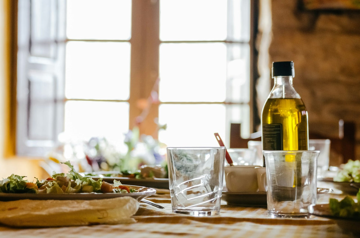 A bottle of olive oil on a table by a window