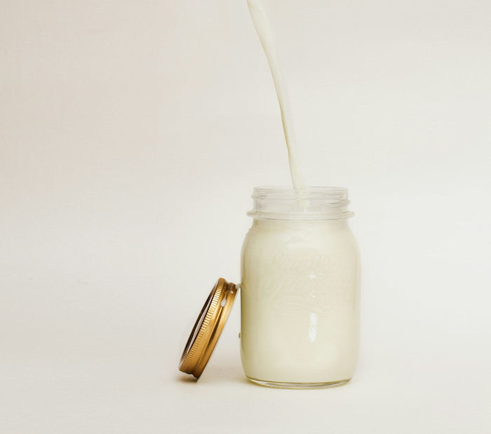 Milk pouring into a glass jar