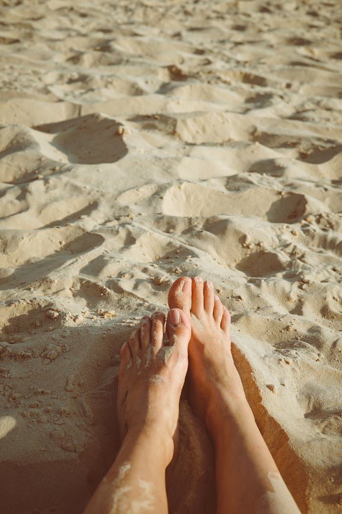 Two bare feet resting on sand