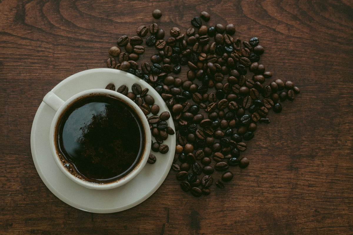 A cup of black coffee with coffee beans