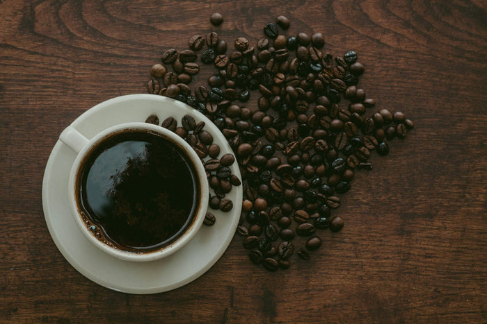 A cup of black coffee with coffee beans