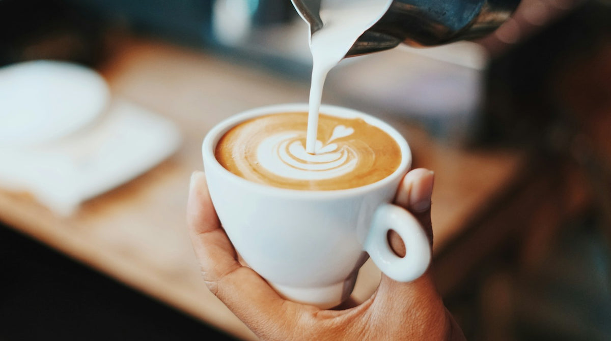 Milk being poured into a cup of coffee