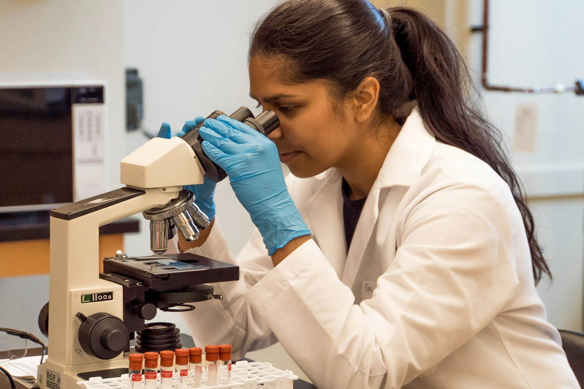 A woman in a lab coat looking into a microscope