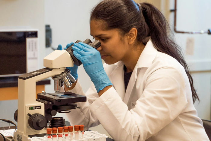 A woman in a lab coat looking into a microscope