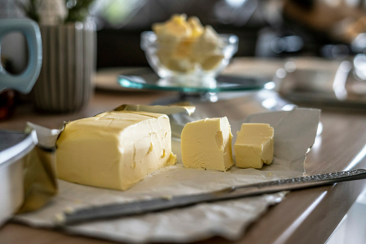 Blocks of butter on paper beside a bowl of butter curls