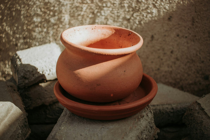 An earthen pot on a clay saucer, the kind used to set curd