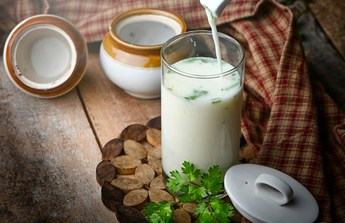 A glass of buttermilk beside clay pots