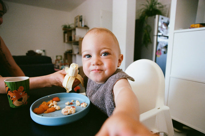 A baby eating fruit at a table