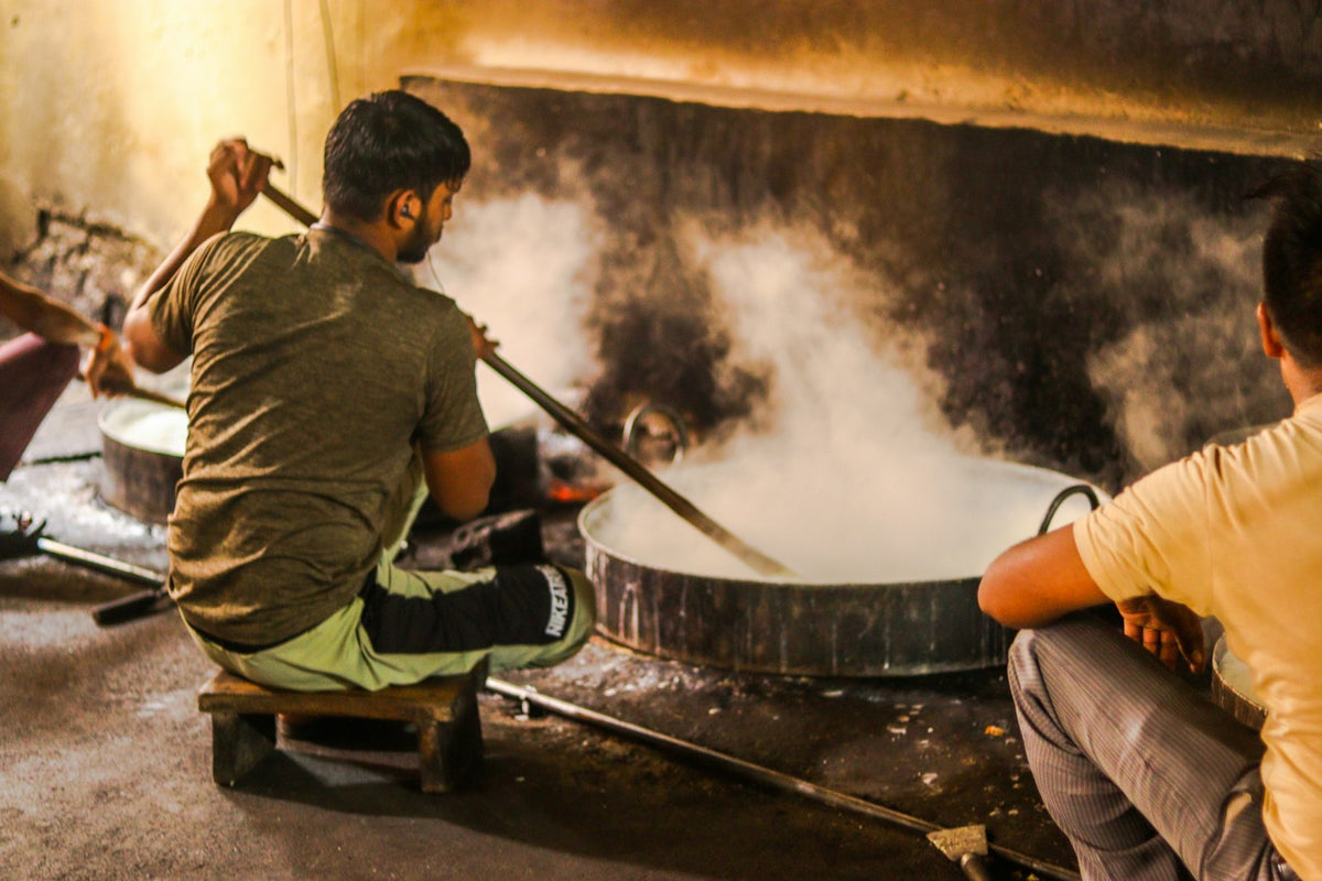 A man stirring a large pan over a wood fire