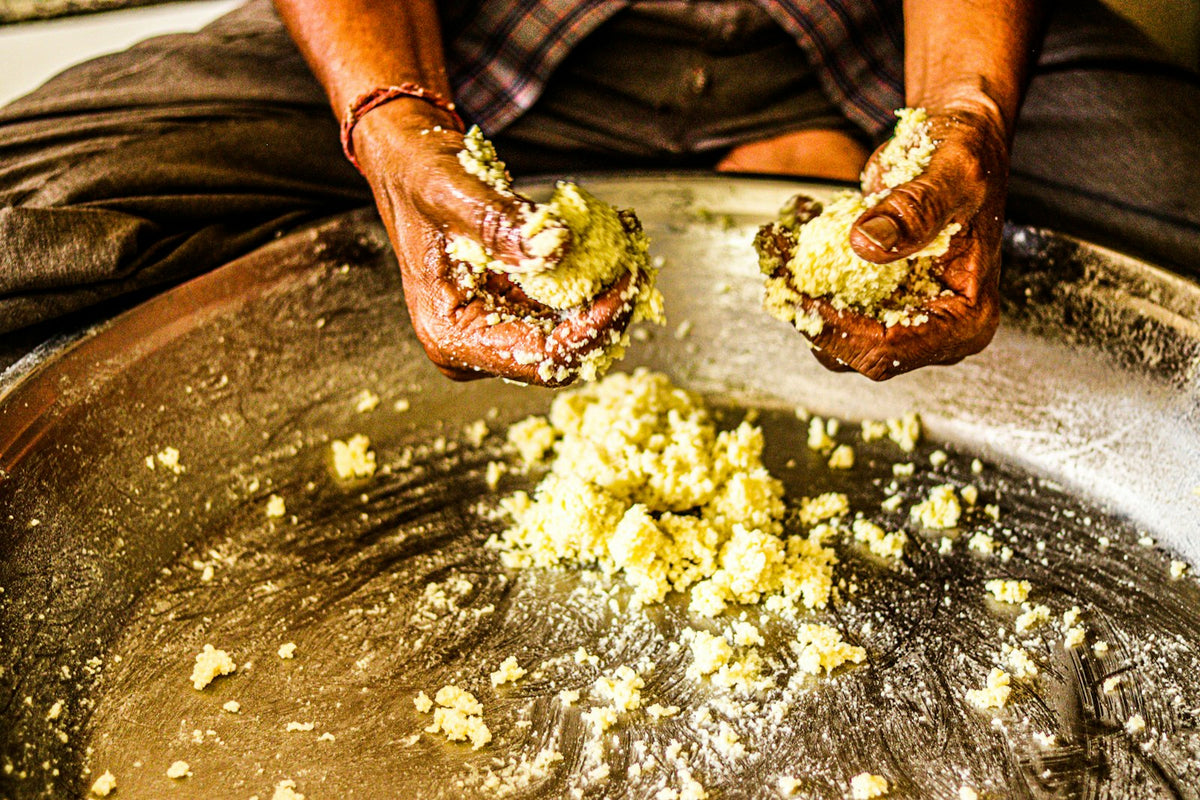 Hands gathering fresh butter from a large pan