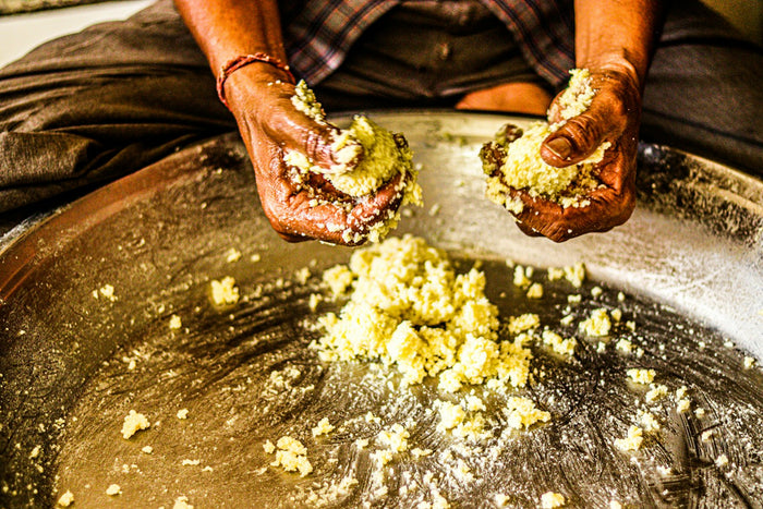 Hands gathering fresh butter from a large pan