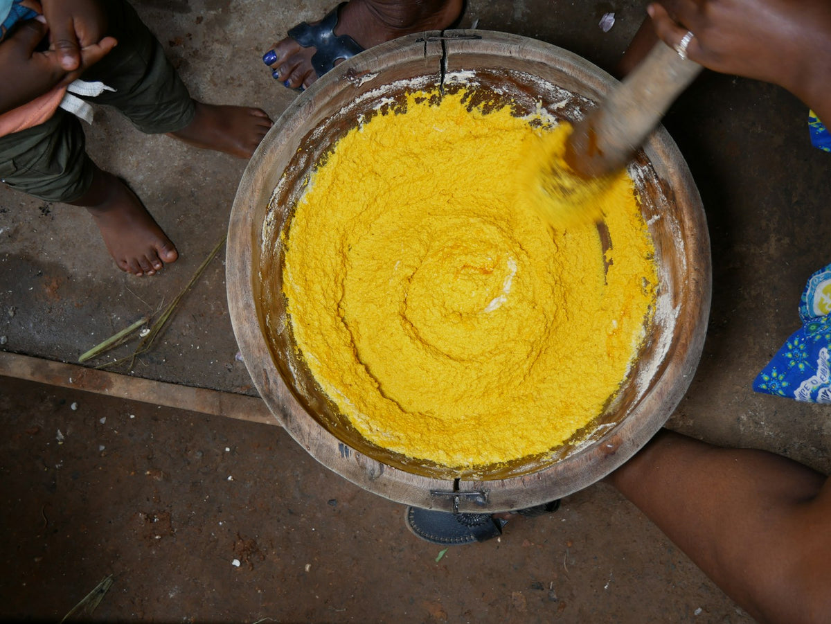 Hands stirring freshly churned butter in a steel bowl