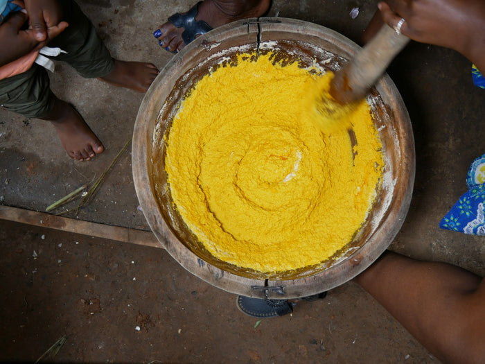 Hands stirring freshly churned butter in a steel bowl