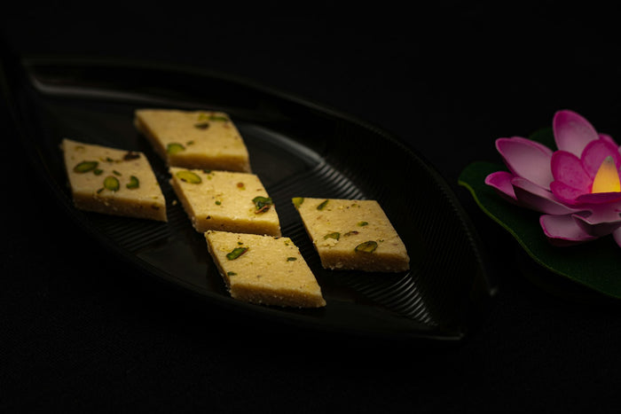 Squares of barfi on a black plate