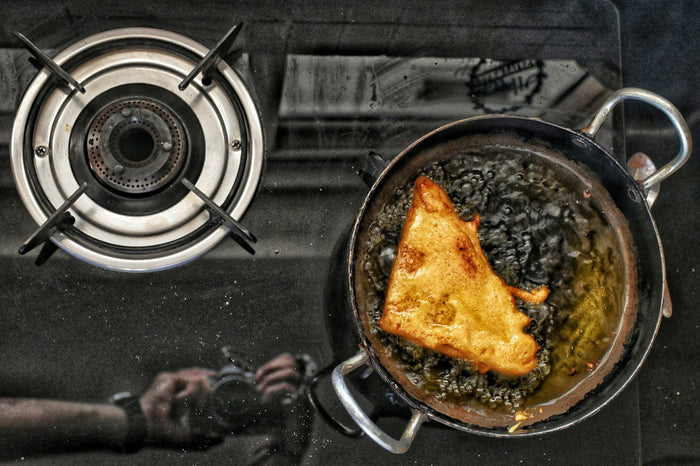 Bread frying in a blackened pan on a gas hob