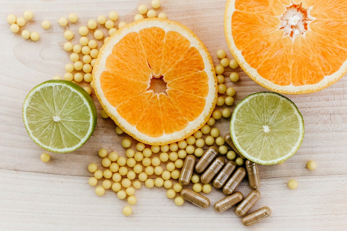 Orange and lime halves beside supplement capsules