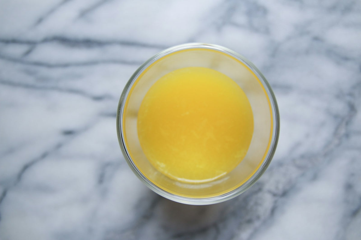 A glass of melted ghee on a marble surface