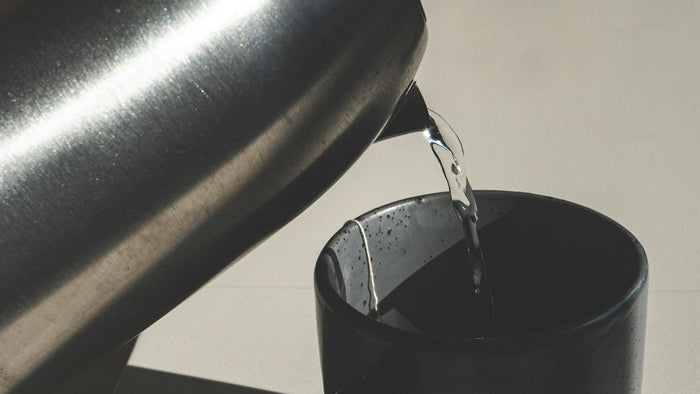 Hot water being poured from a kettle into a cup