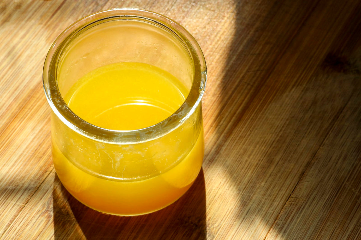 A glass jar of liquid ghee lit by sunlight