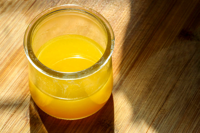 A glass jar of liquid ghee lit by sunlight