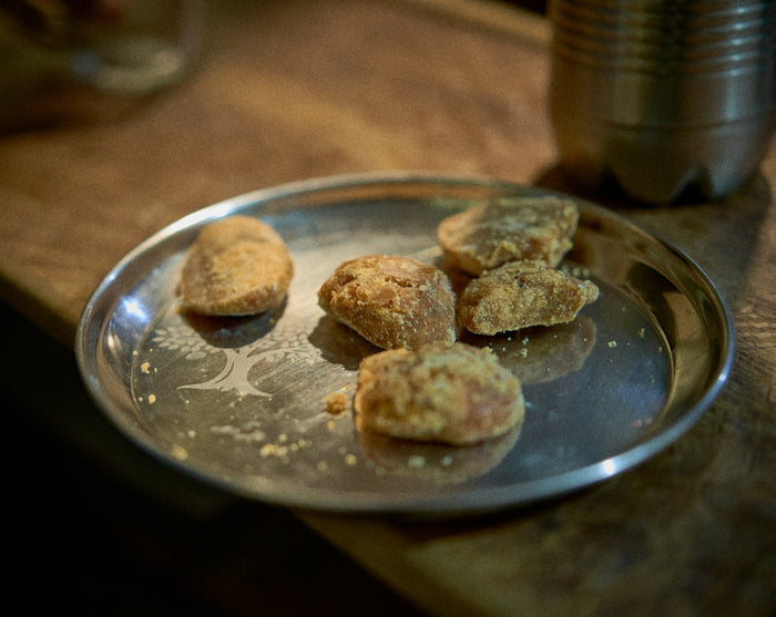 Five pieces of jaggery on a steel plate engraved with a tree